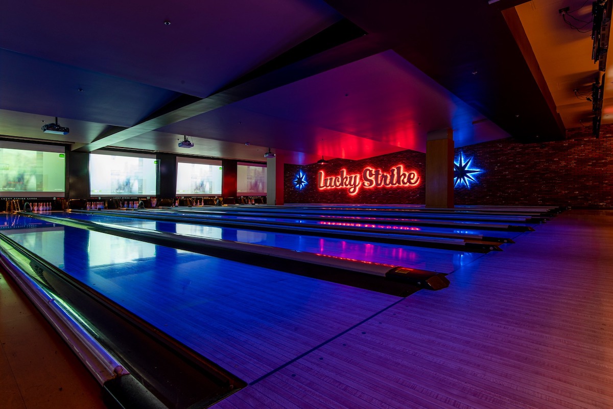 A darkened bowling alley with a neon sign reading "Lucky Strike."