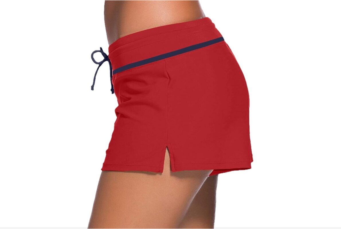 A pair of red board shorts featuring a navy blue trim detail.