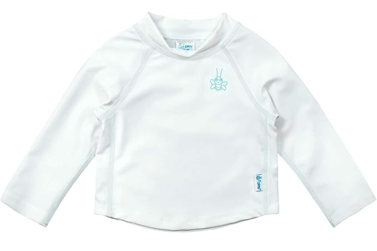 A white long-sleeve baby UV top with a small blue logo of a stylized insect near the collar and the brand label "i play." on the side seam. The fabric appears to be lightweight and designed for sun protection.