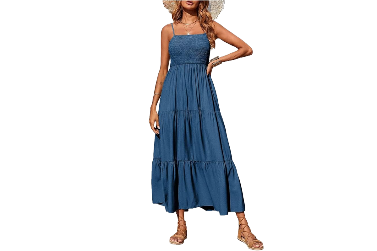 A woman wearing a blue midi dress with a smocked upper, spaghetti straps. She is wearing straw hat.