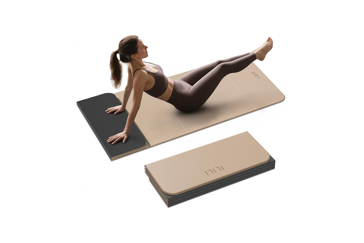 A woman in a yoga pose is sitting on a cream and brown yoga mat.