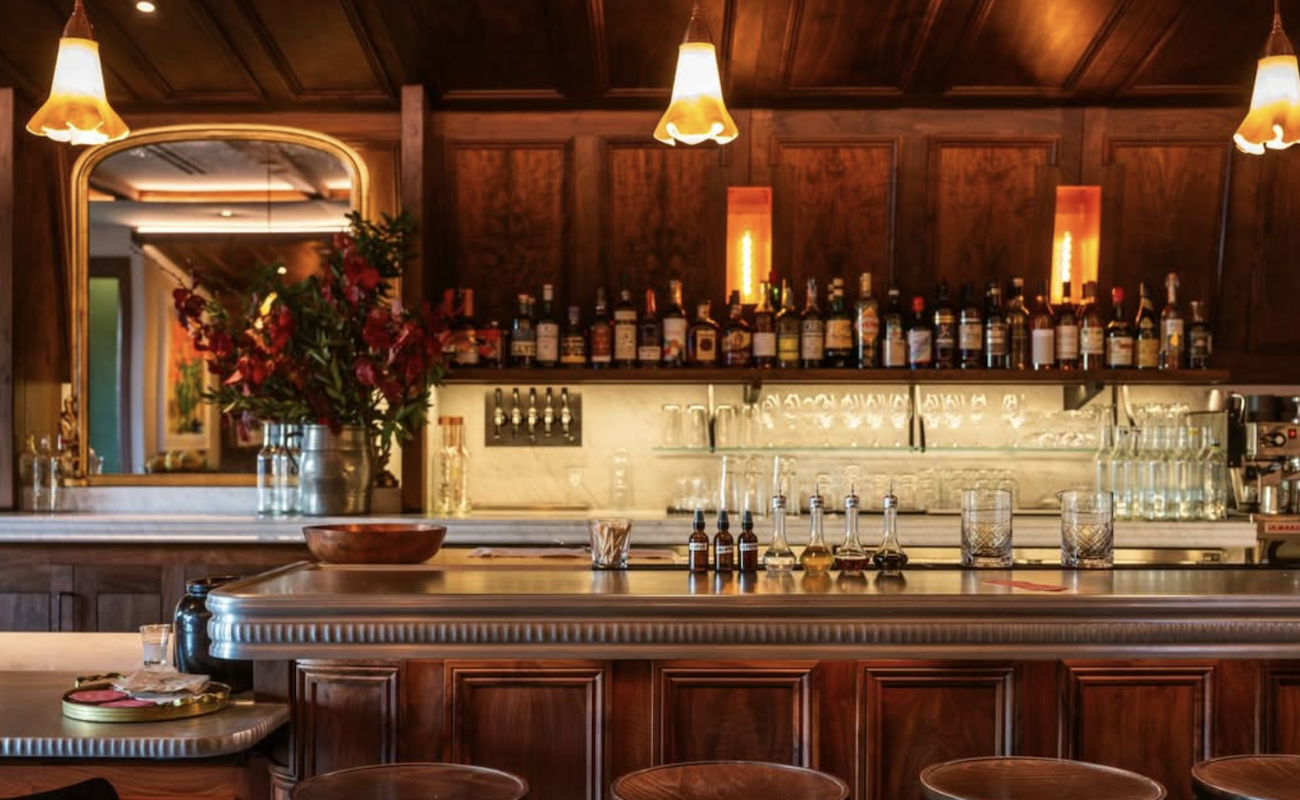 A bar with dark brown wood features and mood lighting.