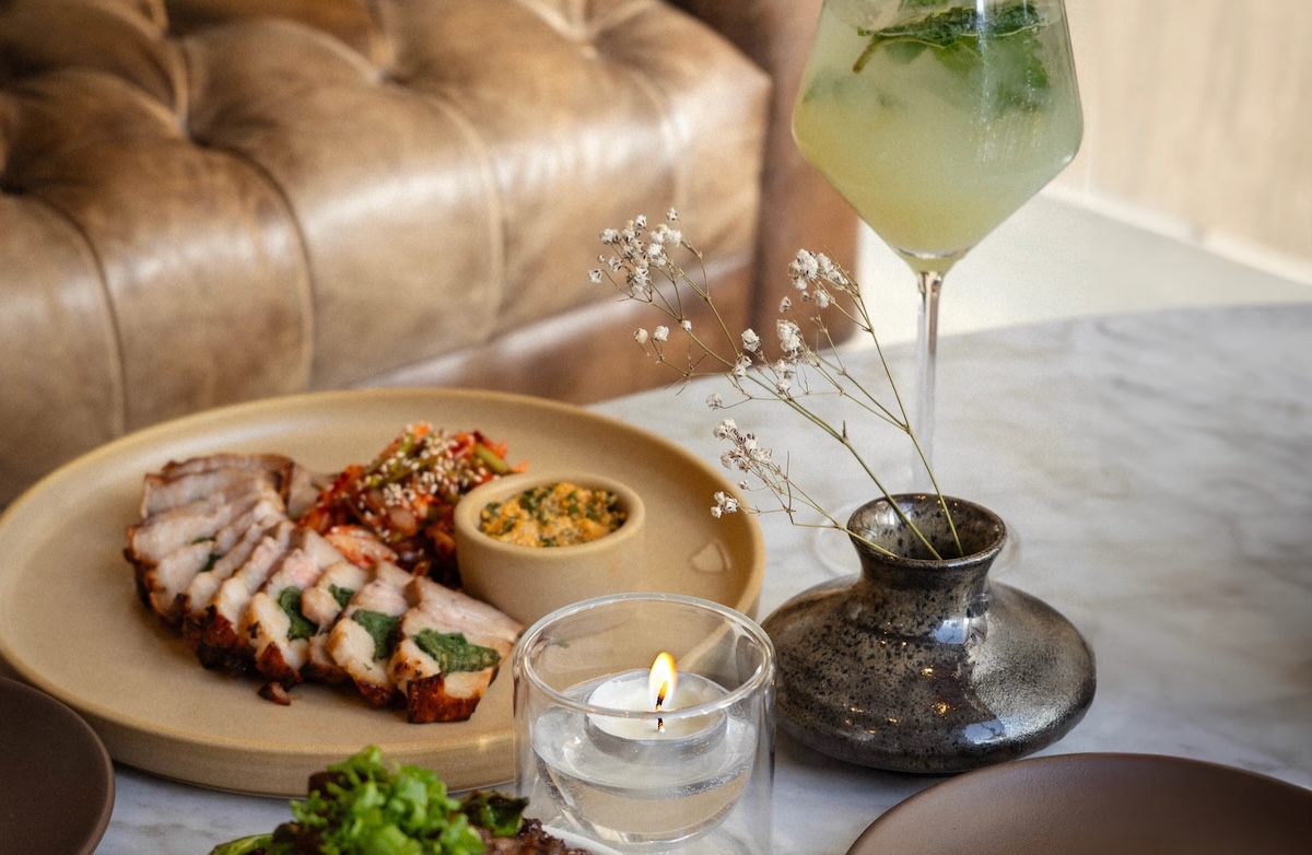 A table setting with plates of elevated food and a greenish cocktail, Buoy Bar.