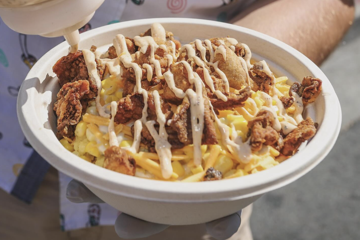 A paper bowl with fried mushroom, mashed potatoes and a cajun ranch drizzle.