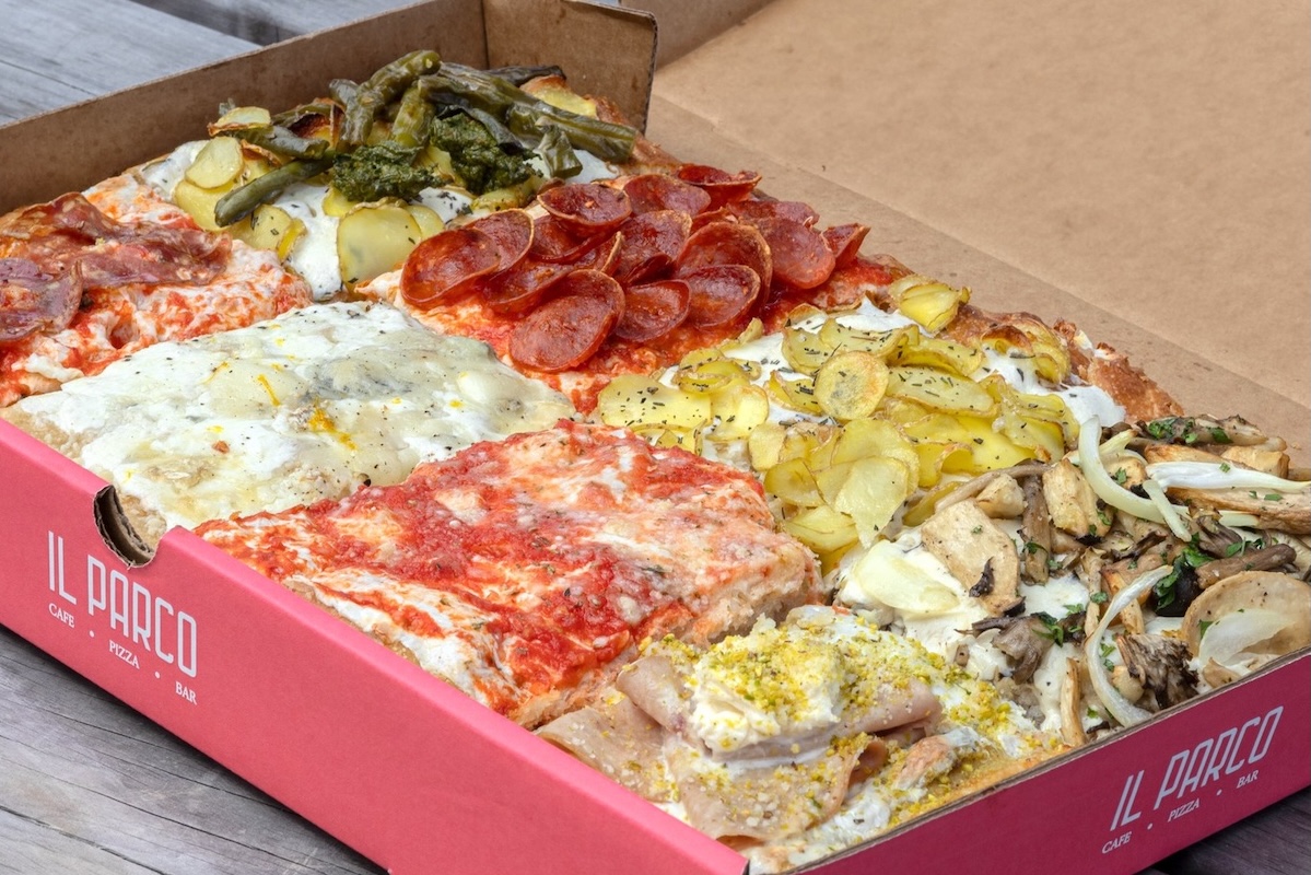 A large pizza box with many different small pizzas with toppings including lots of cheese, pepperoni, sliced meat, mushrooms, onions, potatoes, broccoli, green beans and more.