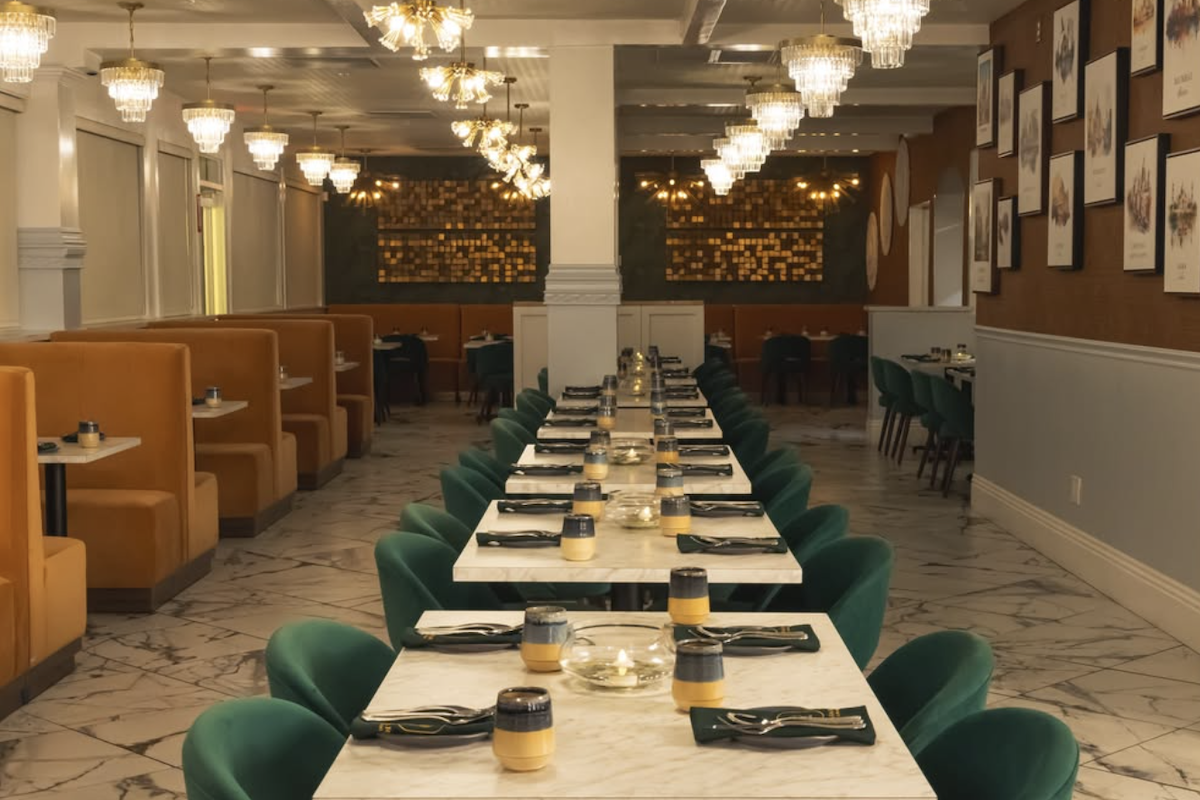 A long table with teal chair is set in a restaurant.