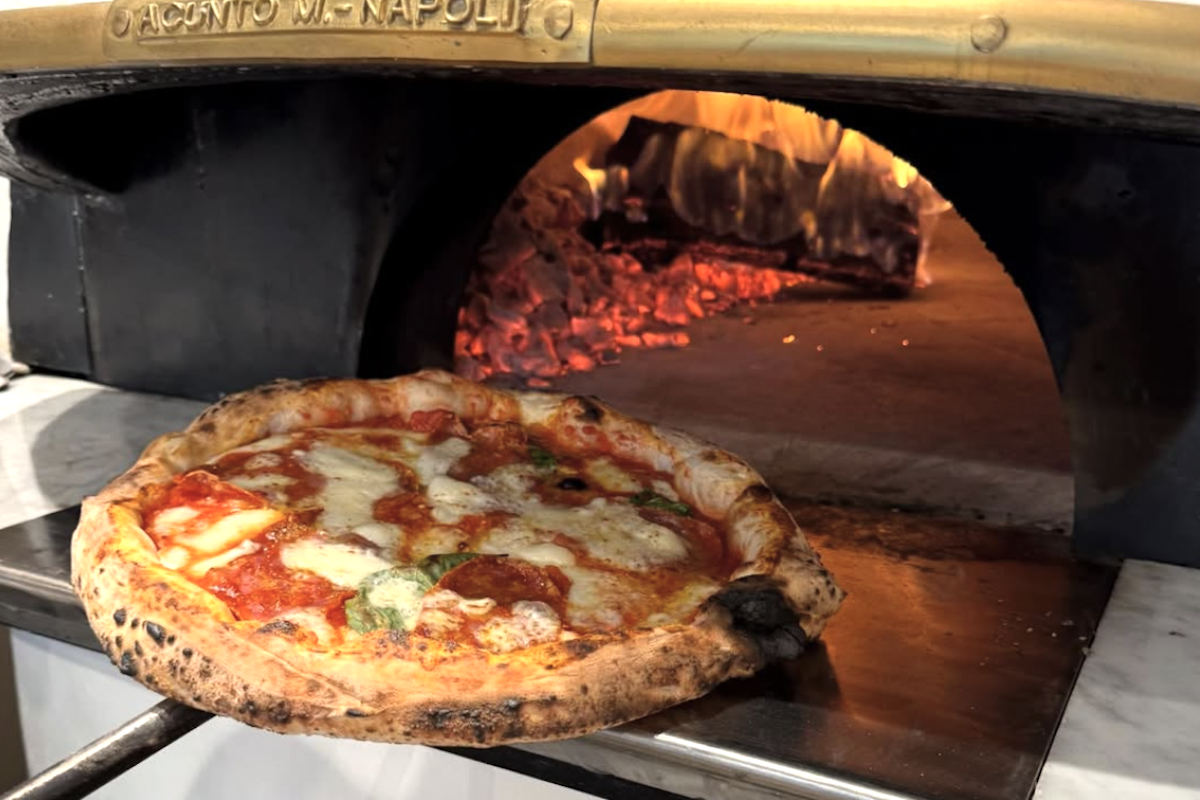 A pizza being pulled out of a pizza oven.
