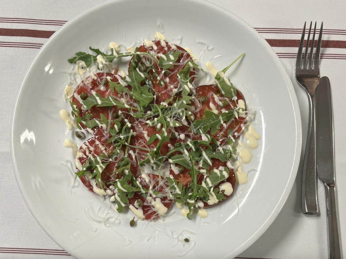 Plate of arugula, tomatoes and a white cream sauce.