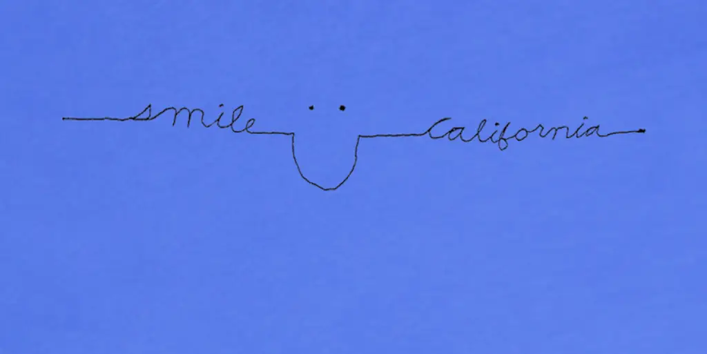 The image features the words "smile" and "california" written in black cursive, seamlessly connected with "smile" on the left and "california" on the right. They form a simplistic smiley face with small eyes in the middle against a blue background, part of a charming smile collection.