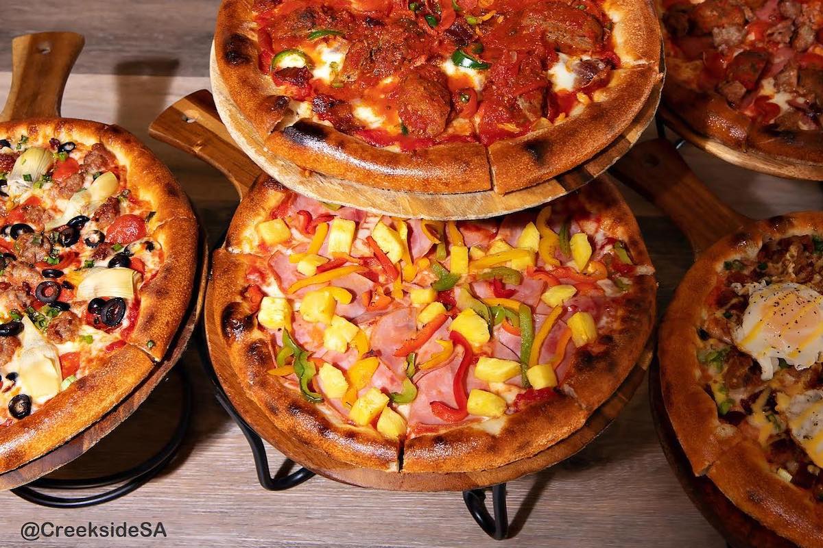 Different types of pizza are displayed on different levels, which toppings that include veggies, ham, pineapple, meat, olives, and more.