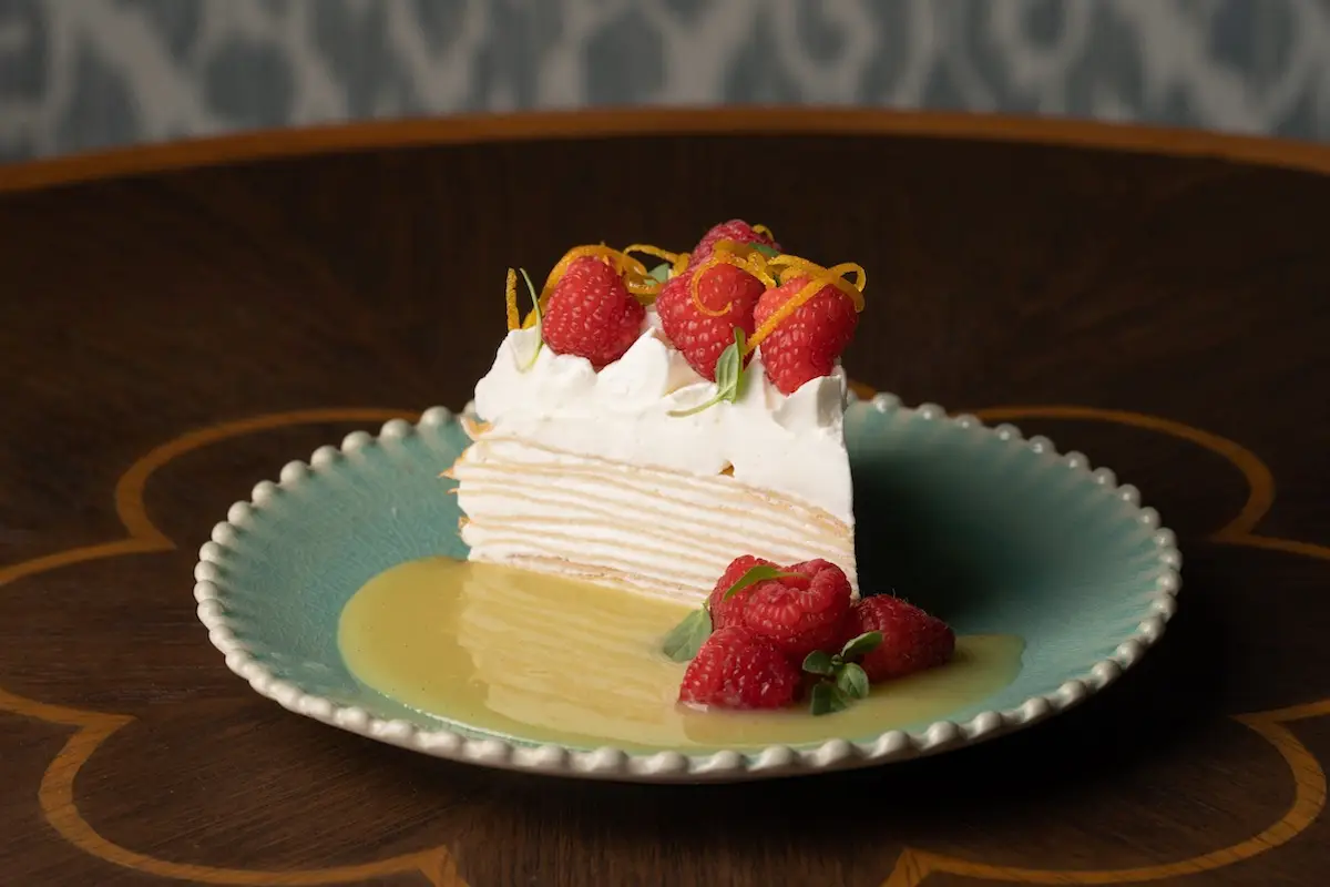 Plate sits on an ornate table with the Lemon crepe cake and raspberries by Bungalow Kitchen in Tiburon, California