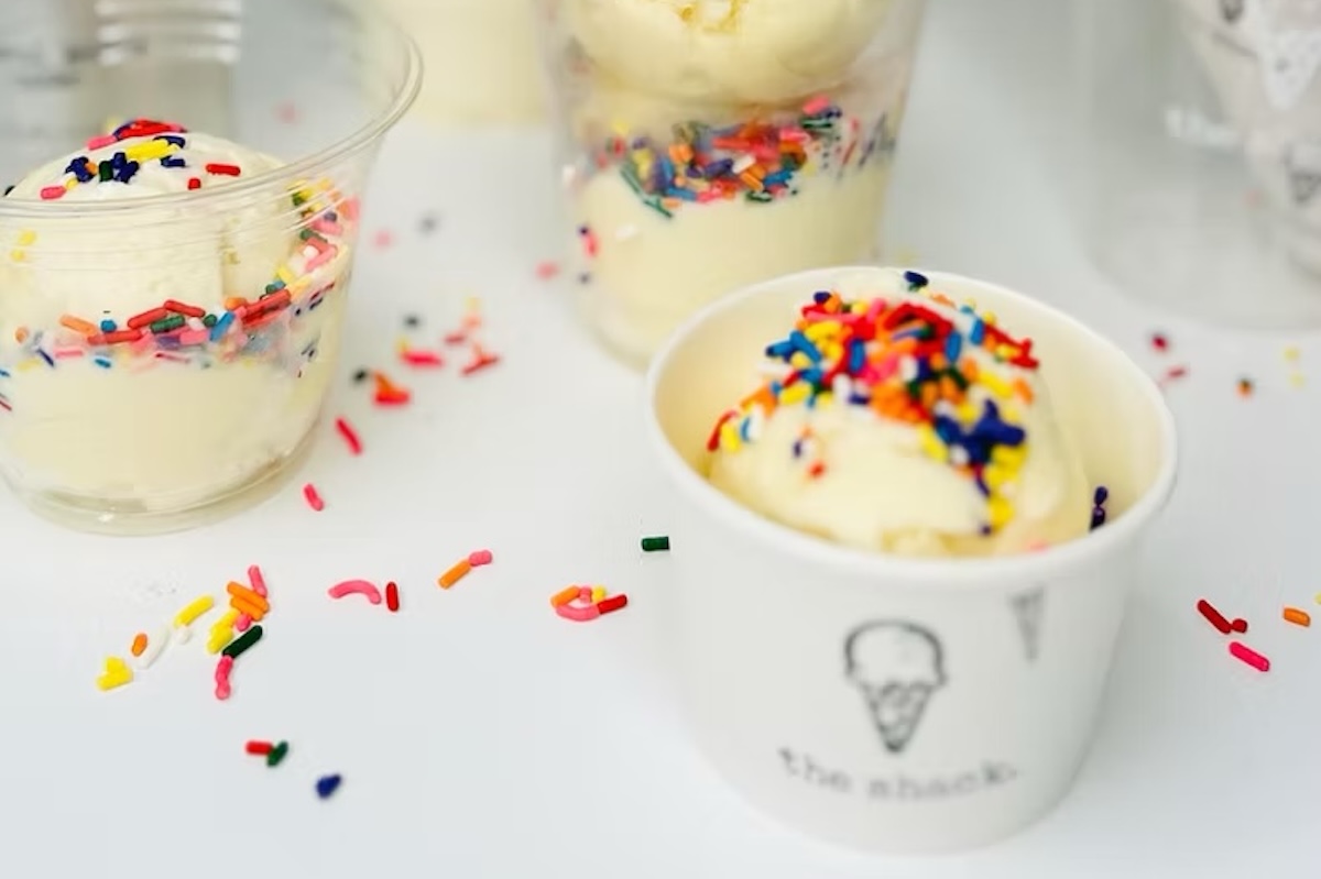 A few cups of vanilla ice cream topped with rainbow sprinkles.