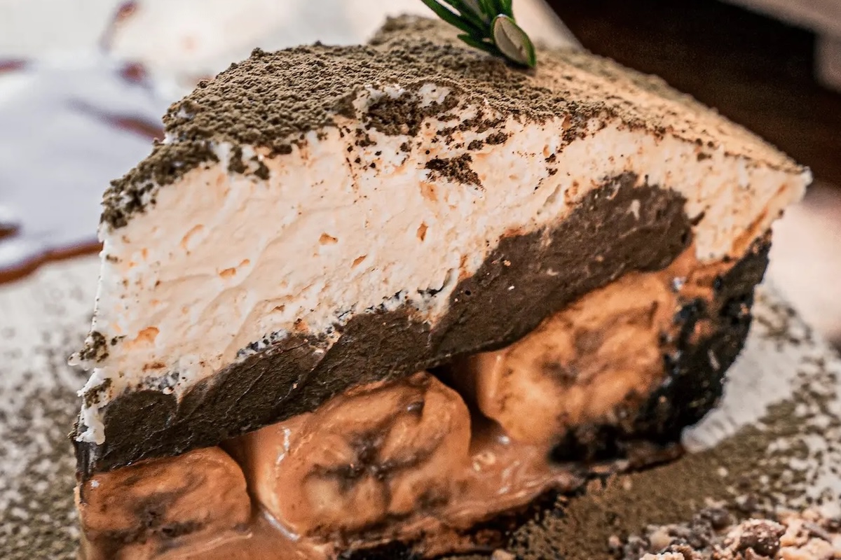 A chocolate pie with a layer of bananas, chocolate crust, cream and dusting of chocolate.