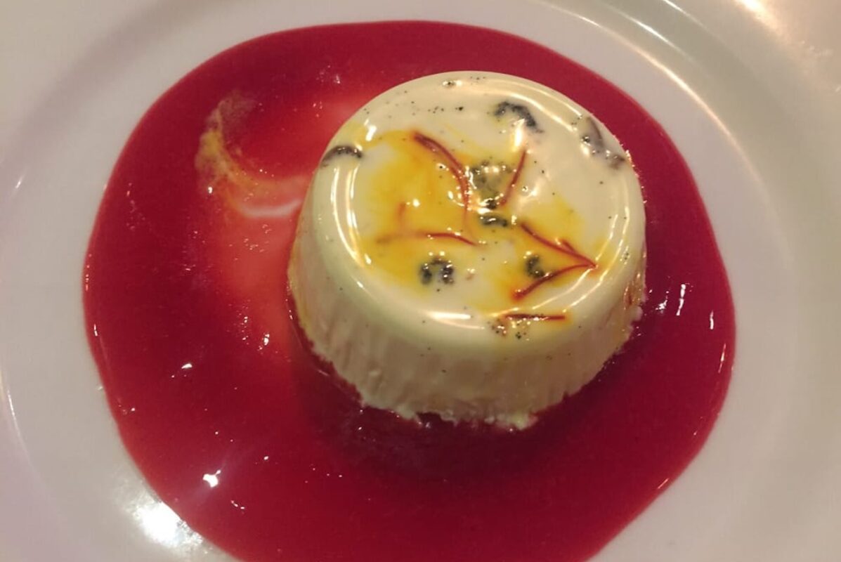 A bright red raspberry sauce with a saffron panna cotta in the center.