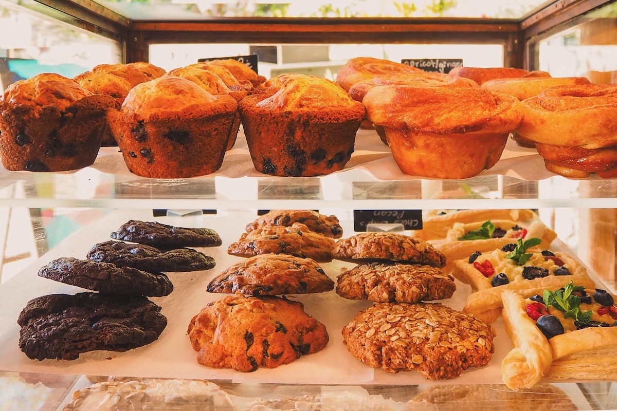 A glass case with different pastries including muffins and scones.