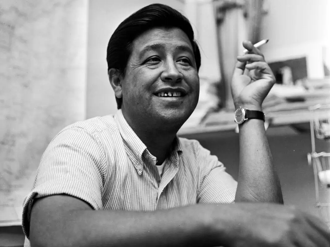 Cesar Chavez labor activist smoking cigarette and smiling, representing upcoming Cesar Chavez Day Parade and Festival in San Francisco, California
