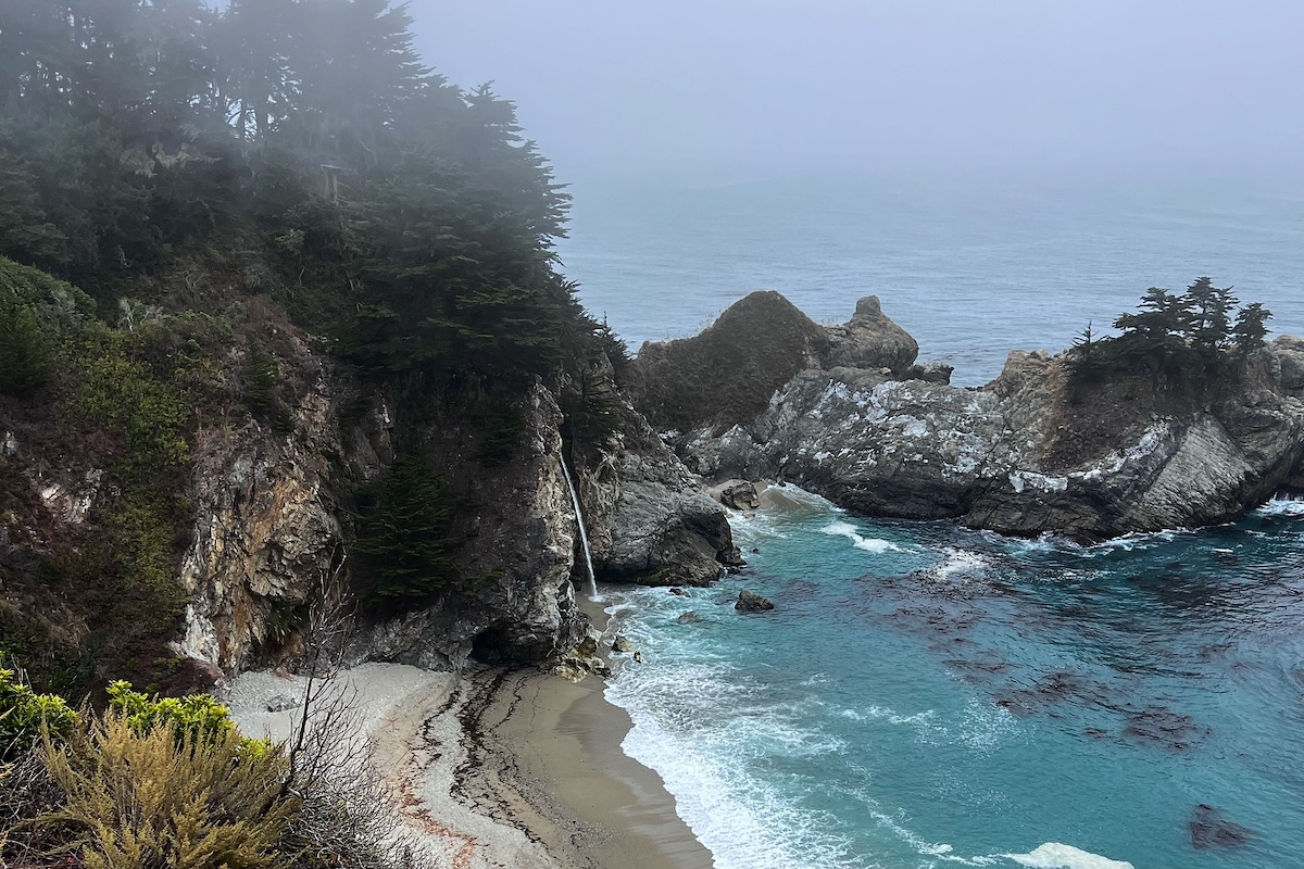 A rocky bluff with a view of a beach and turquoise water below.