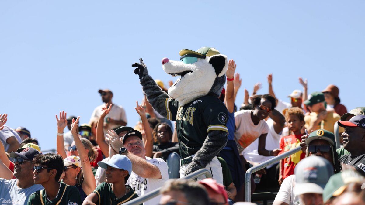 Rat mascot of Oakland Ballers baseball team cheers with fans in a crowd