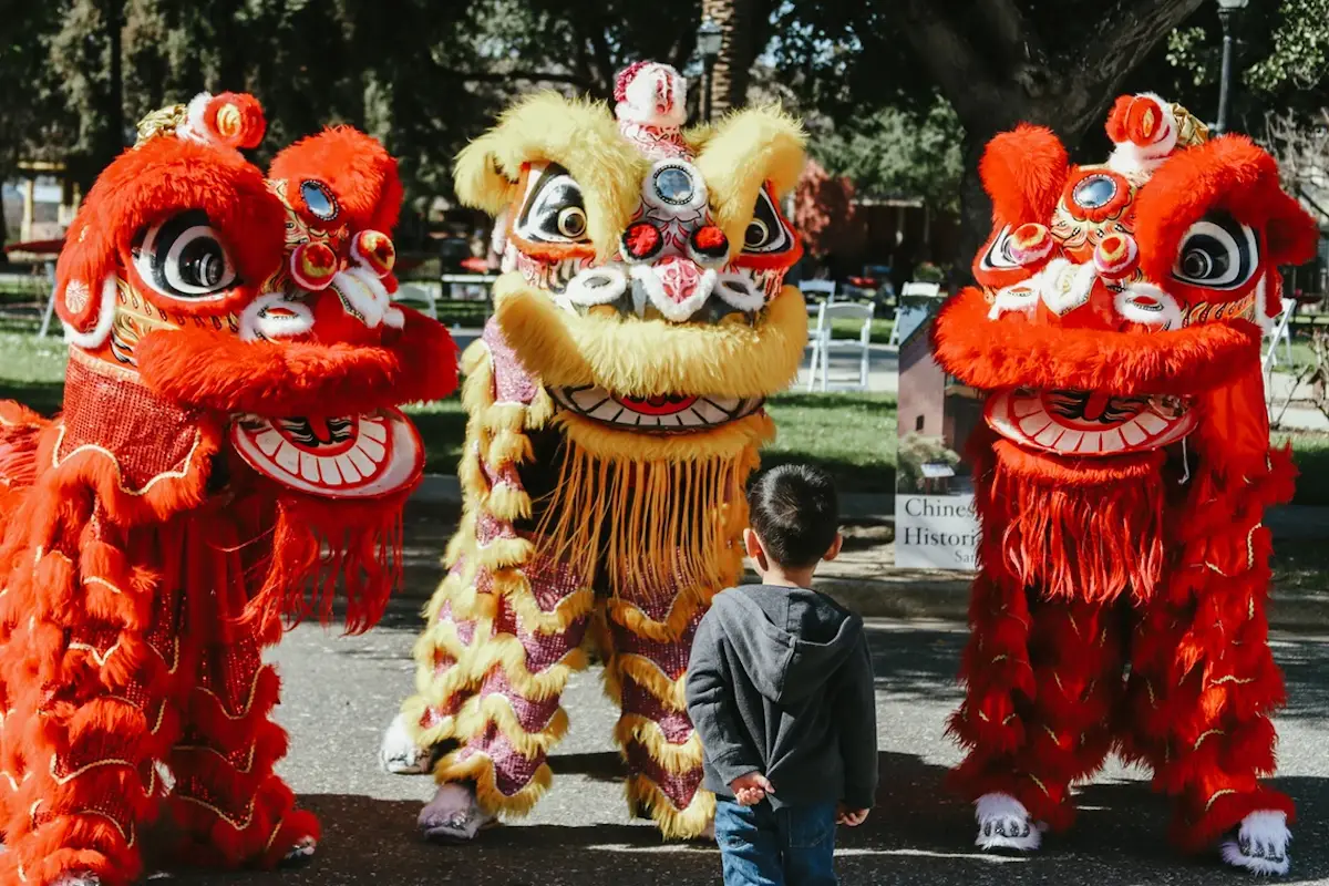 Child stands with lion dancers at the South Bay AAPI Festival in San Jose, California.