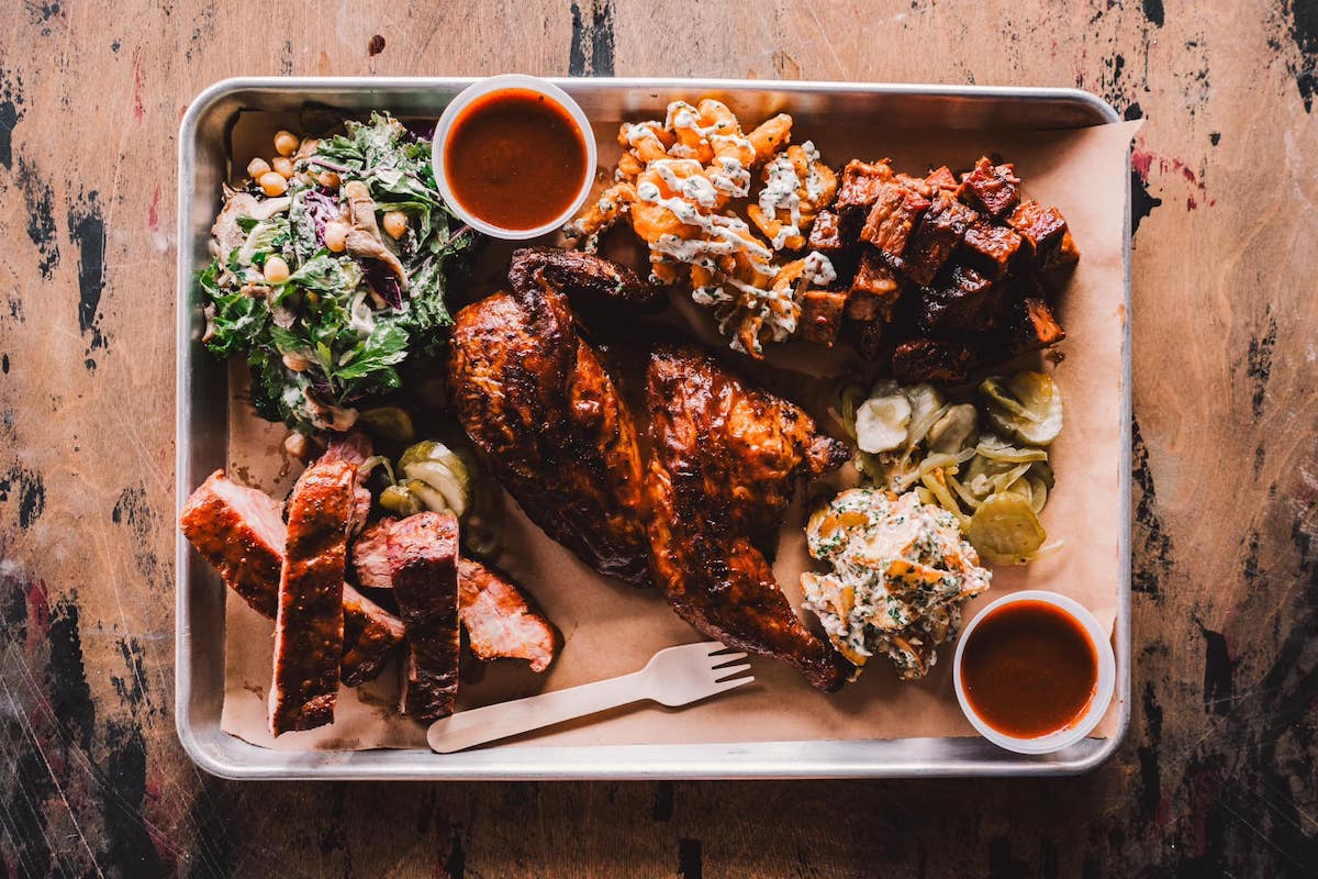 Barbecued meat with sides including salad, pickles and more.