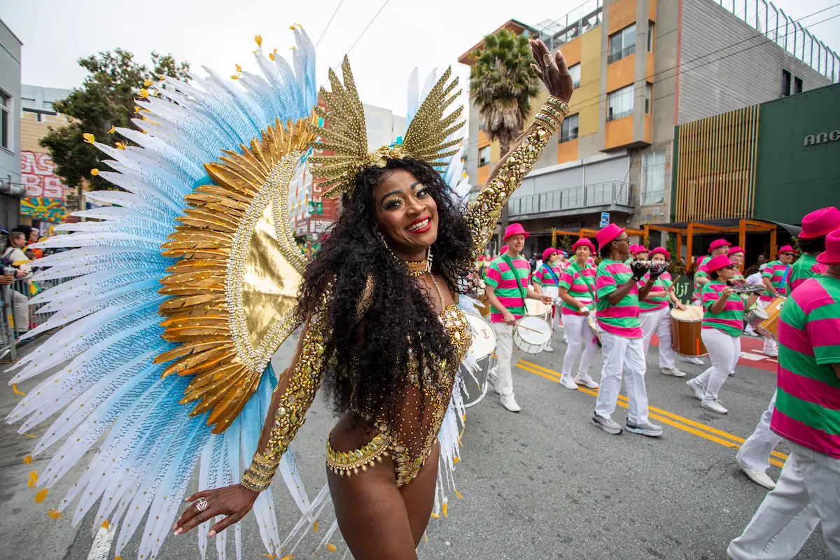 Carnaval performer in gold costume with feathers at Carnaval parade and festival in San Francisco, California