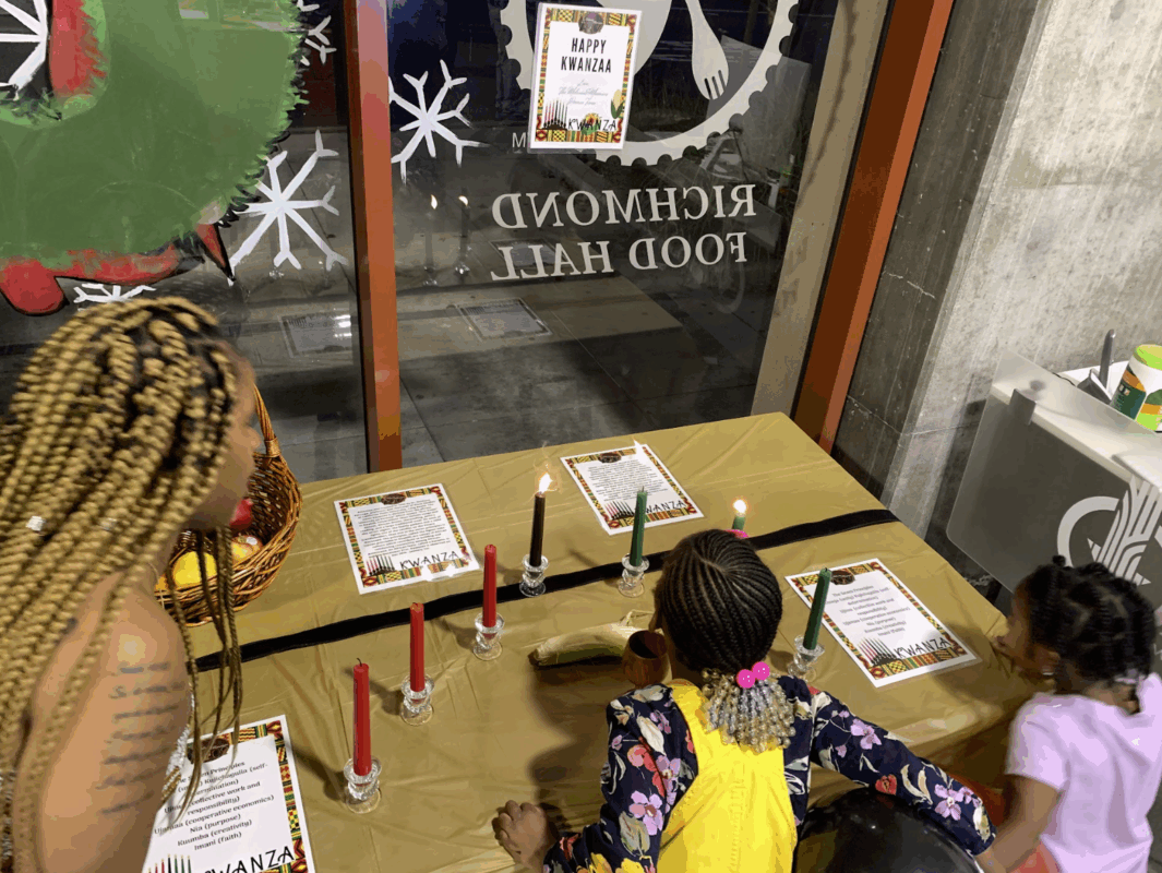 A woman and two kids lighting candles for Kwanzaa