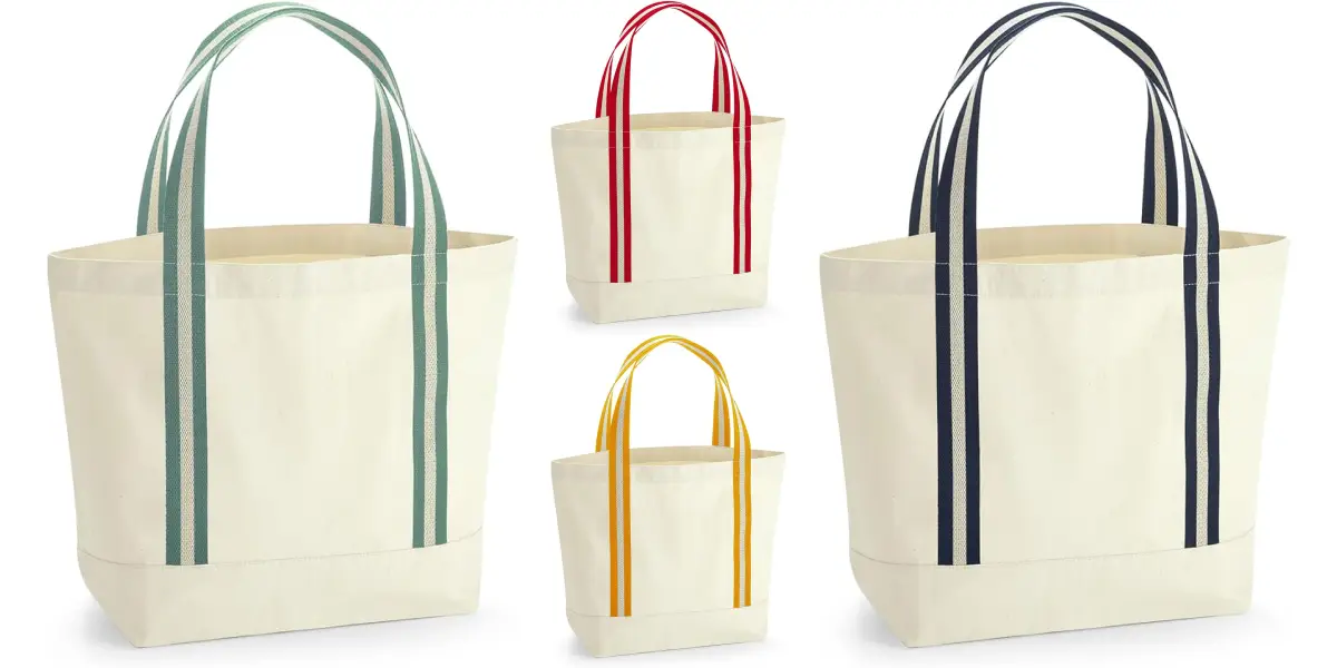 A collection of four sustainably-made beach bags with different colored handles. The beige totes feature handles in green, red, yellow, and navy blue. The bags are arranged such that the green and navy blue handled totes are larger, while the red and yellow handled totes are smaller.