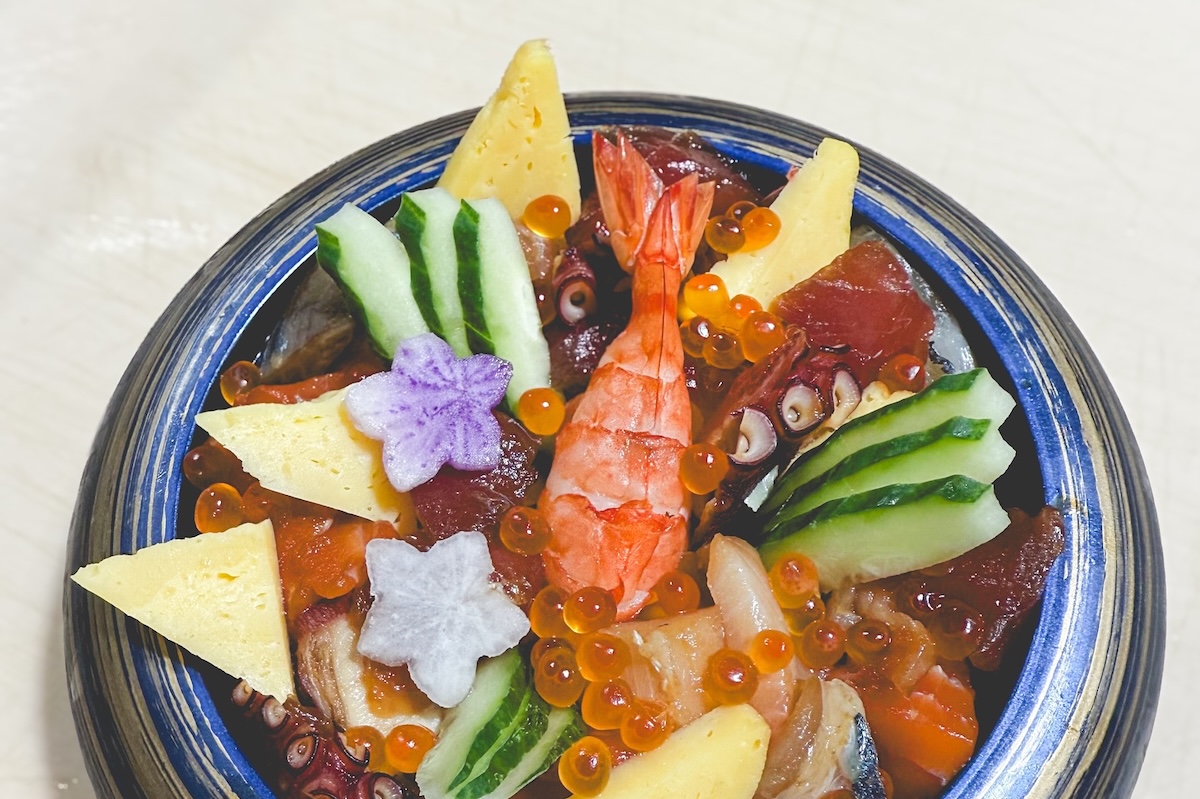 A sushi bowl, with cucumber, pineapple, fruit cut out in the shape of stars, prawns, roe and more.