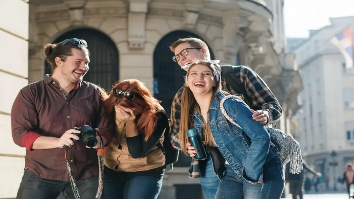 A group of four friends is enjoying a day out in the city. They are all smiling and laughing, one person holding a camera to capture the moment. With historic architectural buildings in the background, it seems they’ve found some of the best things to do on Monterey Peninsula July 2022.