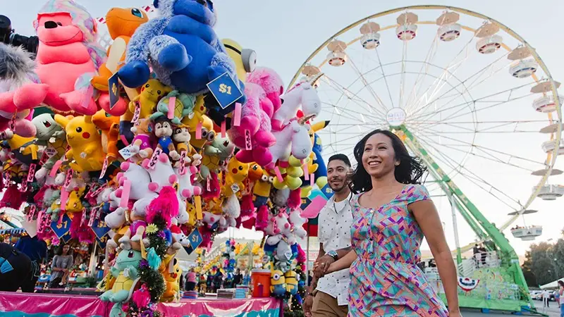 Couple walks past booth with toys at Alameda County Fair