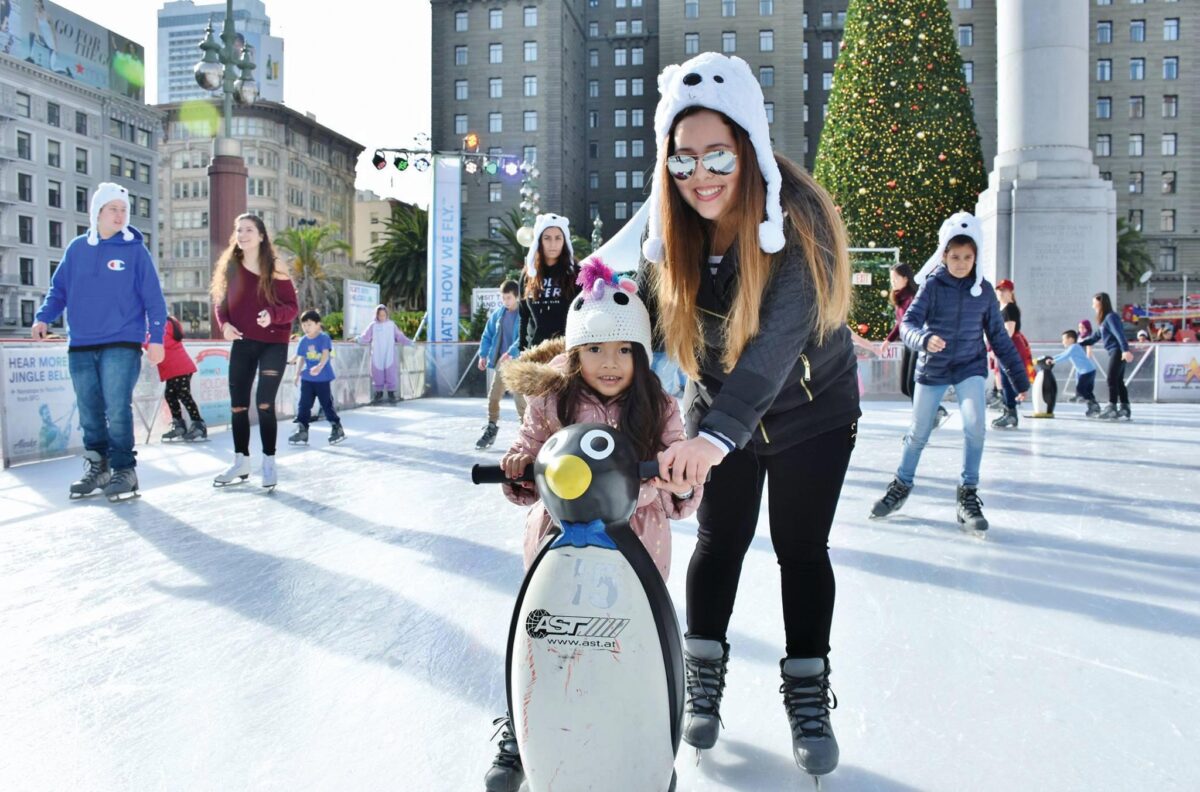 Mom helps child on Union Square ice rink.