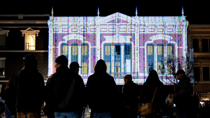 Silhouettes of people in front of projection of house at Napa Lighted Art Festival