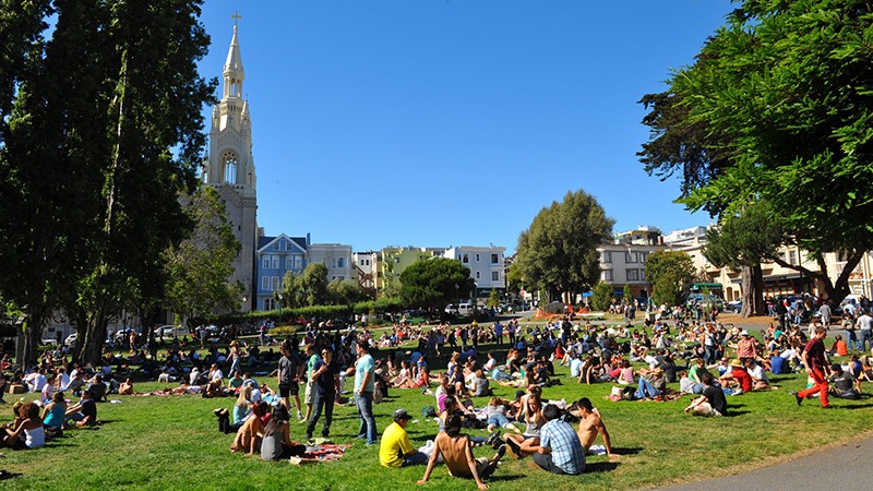 Crowd of people sits in grass at Washington Square at San Francisco's North Beach Festival