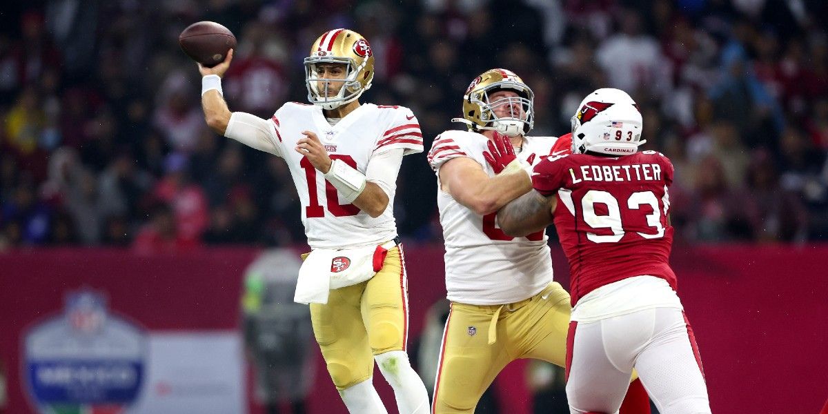49ers quarterback makes a pass while defender blocks oncoming opponent at 49ers game in Santa Clara