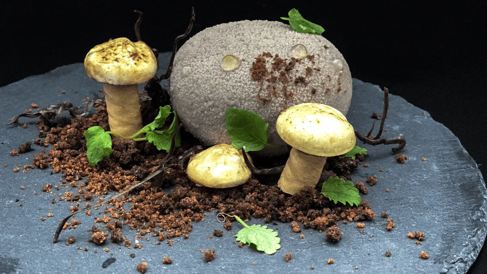 A gourmet dish resembling a forest floor, featuring three mushroom-shaped elements, leafy greens, and crumbled, soil-like garnish on a dark, round slate platter. The artistic presentation emphasizes earthy tones and textures, making it one of the Best Desserts in the Bay Area.