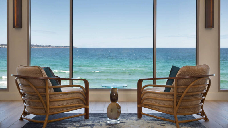 Two chairs face a window with a view of Monterey Bay at Monterey Tides hotel