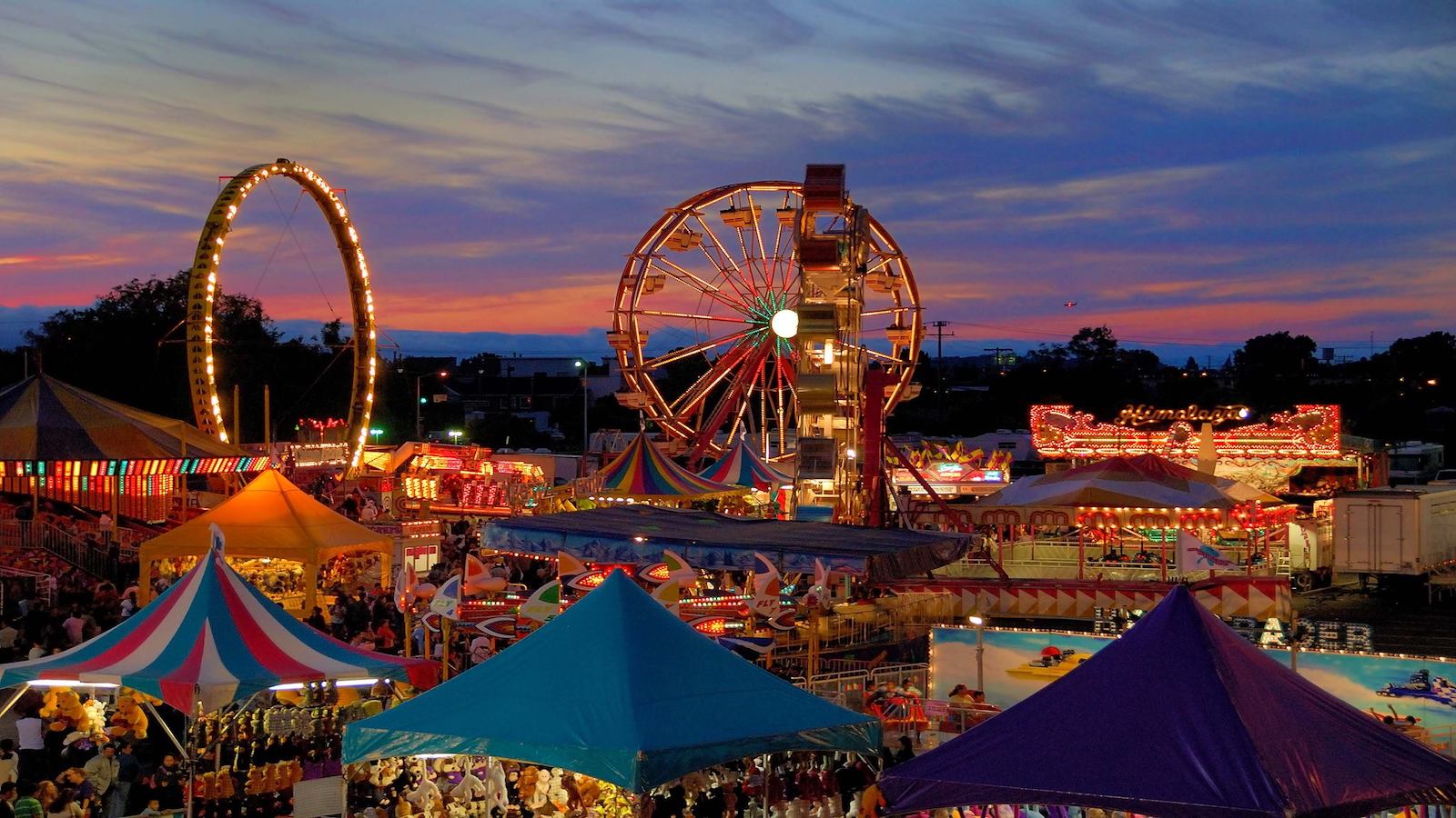 San Mateo County Fair ferris wheels and tents lit up at sunset