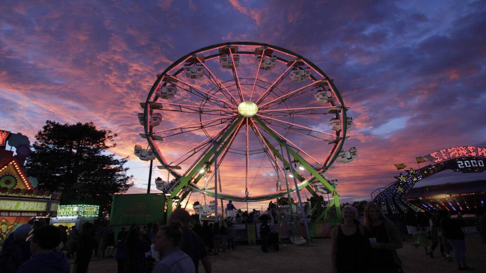 Ferris wheel at Sonoma Marin Fair lit up by sunset and pink clouds