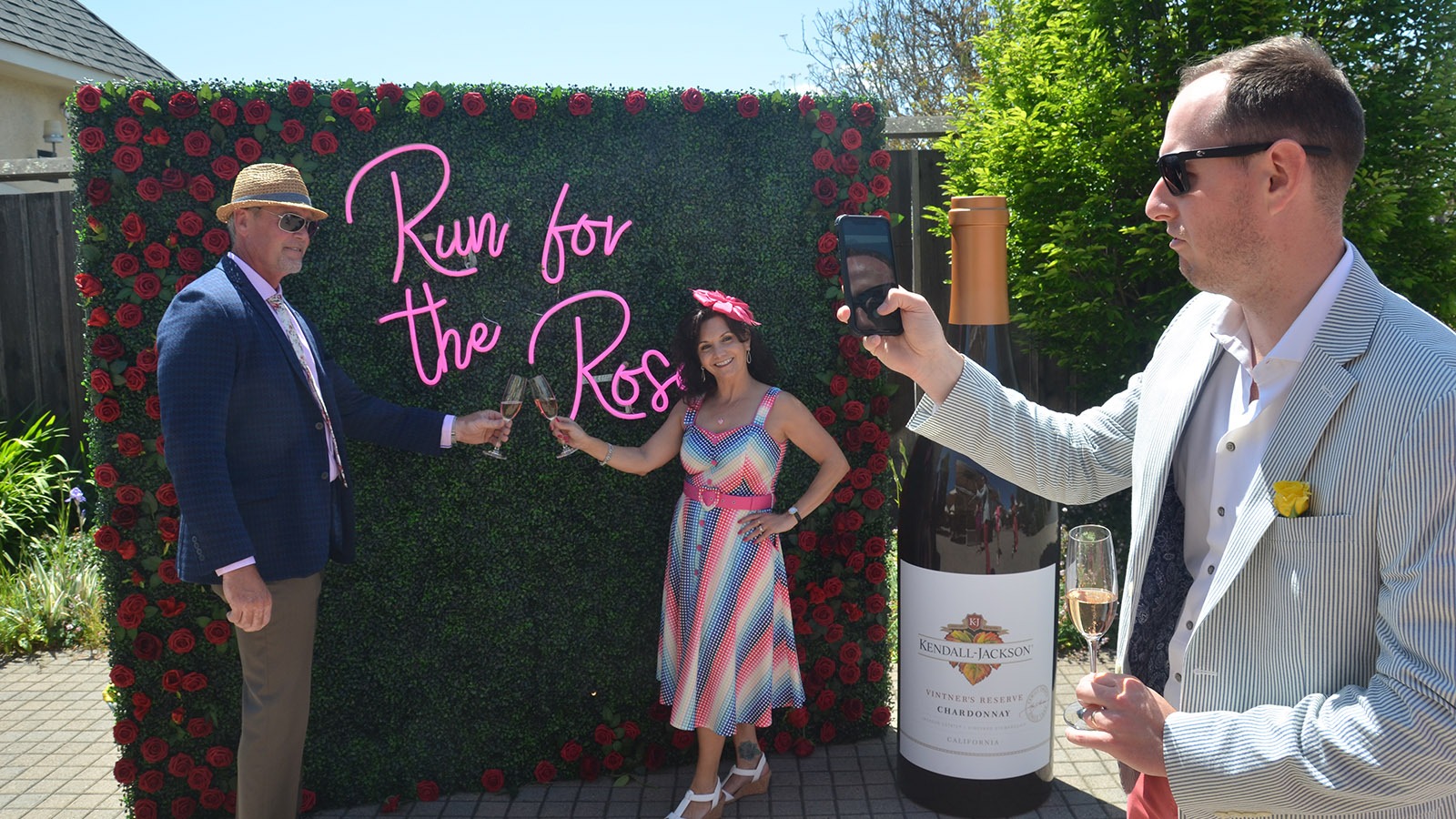 Couple poses in front of sign for Kendall-Jackson Wine Estate's Kentucky Derby party in Sonoma County, California.