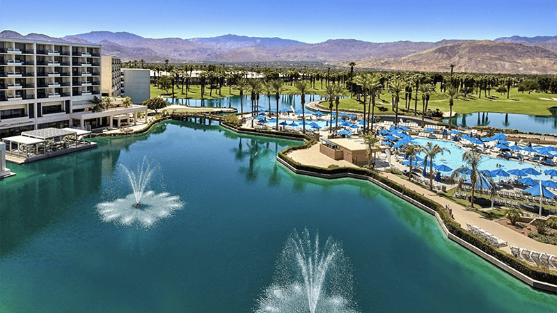 Two decorative fountains spew water in front of Golf Desert Springs' pool and golfing green