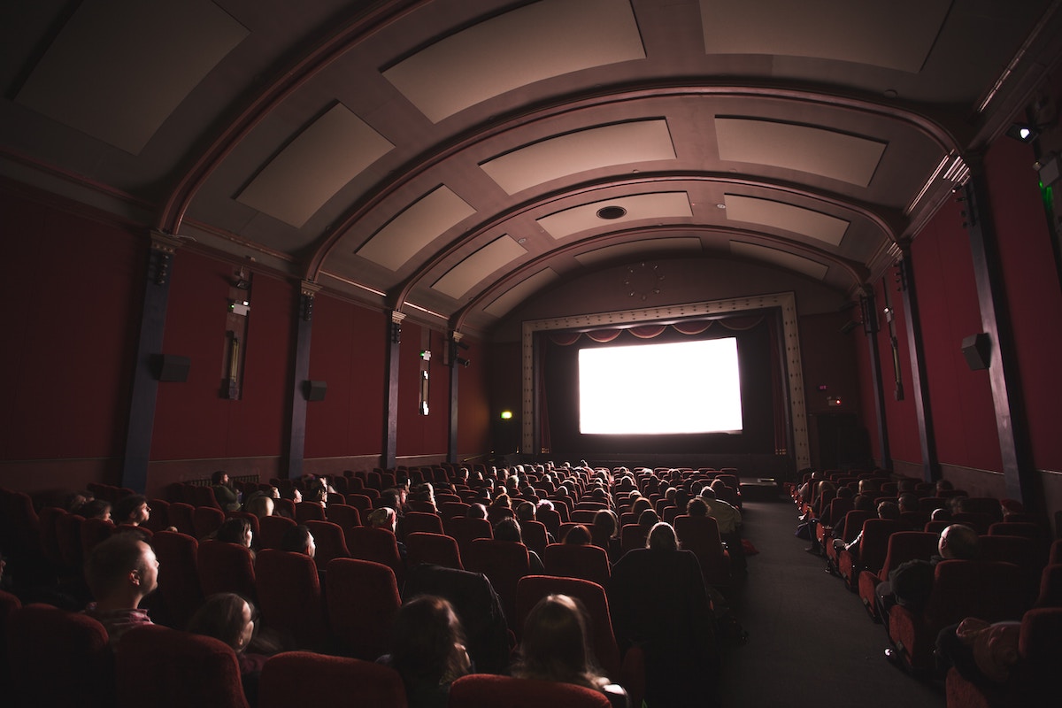 Movie theater filled with people, blank screen being projected