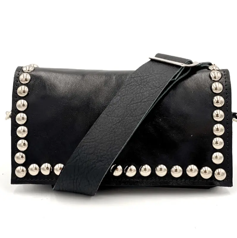 A black leather shoulder bag with a wide strap, designed by Lynn Tallerico. The edges of the bag are adorned with silver studs, creating a border around the flap and sides. The strap is attached with a silver buckle.