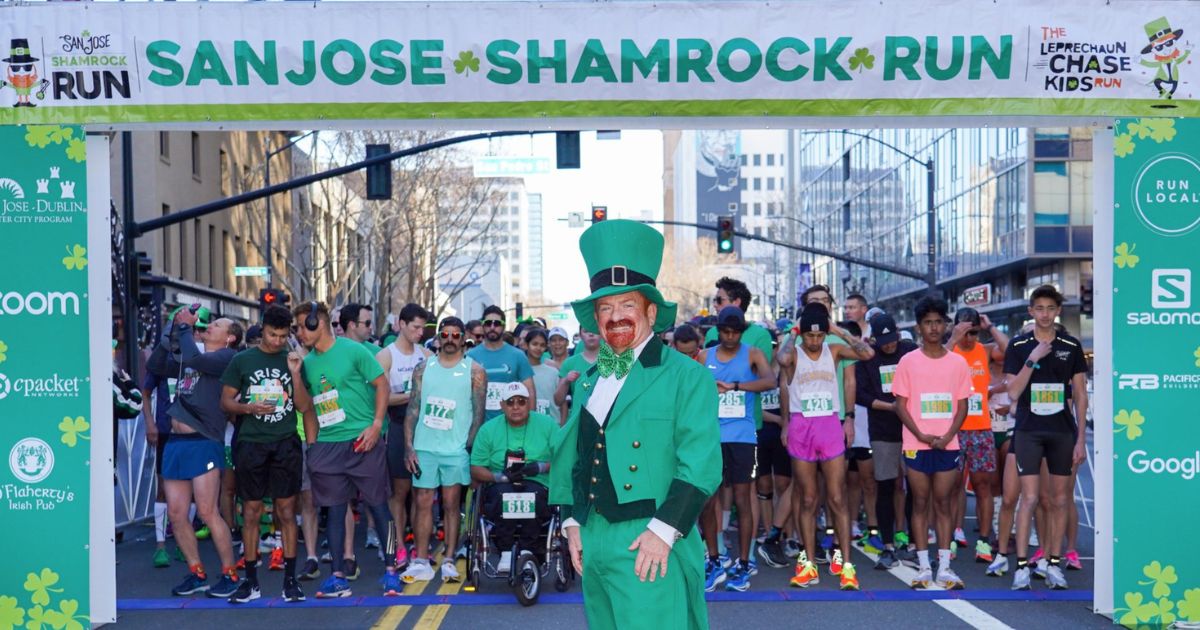 Man in leprechaun suit stands in front of San Jose's Shamrock Run Starting point