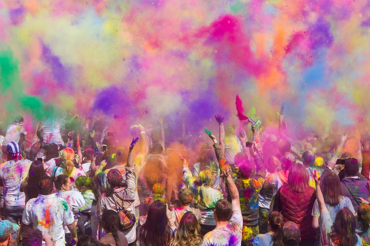 People throw colored dye into air for Holi