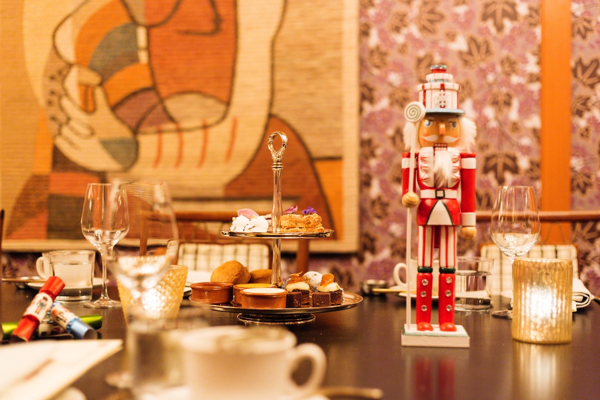 Table setting with wine stems, tea cups, pastries on a tower and nutrcracker