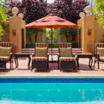 A line of pool chairs and an umbrella above a pool at Casa Palmero in Monterey, California.