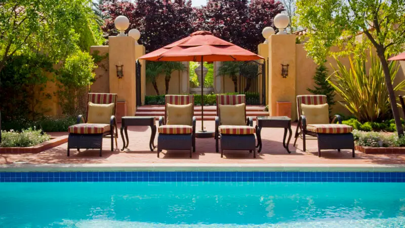A line of pool chairs and an umbrella above a pool at Casa Palmero in Monterey, California.