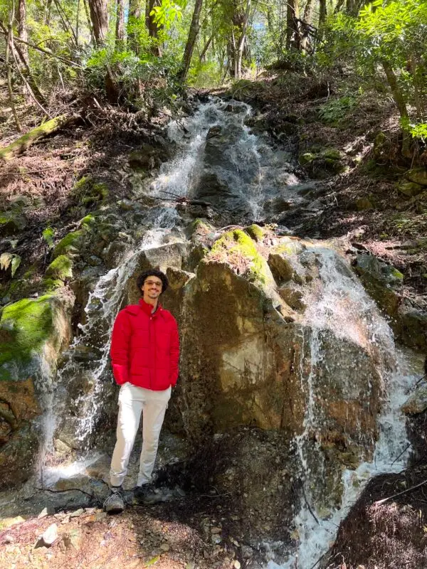 Jordan Reid stands over tall waterfall in Sanborn Canyon Creek waterfall hike in California