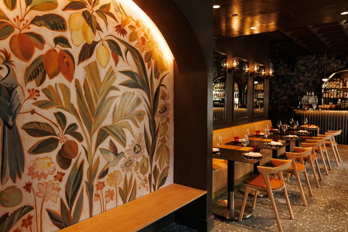 A restaurant interior with a large mural and a view of the bar.