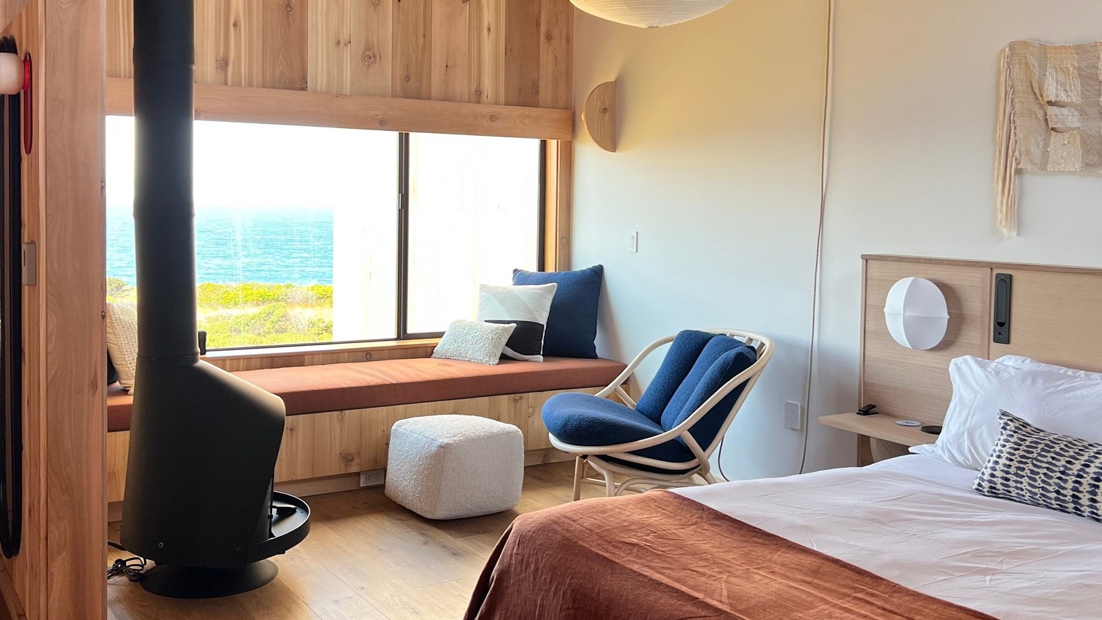 Sea Ranch Lodge room with bed, chair, fireplace, and window with view of the water.